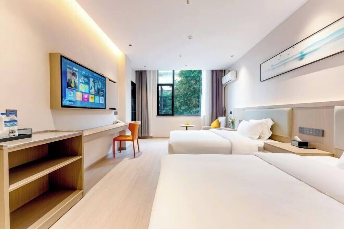 Ein modernes Hotelzimmer mit einem großen Bett, einem Schreibtisch, einem Sessel und einem an der Wand befestigten Fernseher.