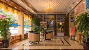 A hotel lobby with a chandelier, seating area, and large windows with a view of the outside.