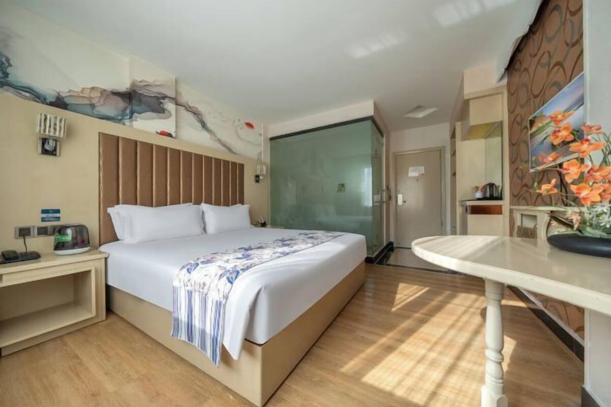 Een hotelkamer met een bed, nachtkastje en een glazen scheidingswand.