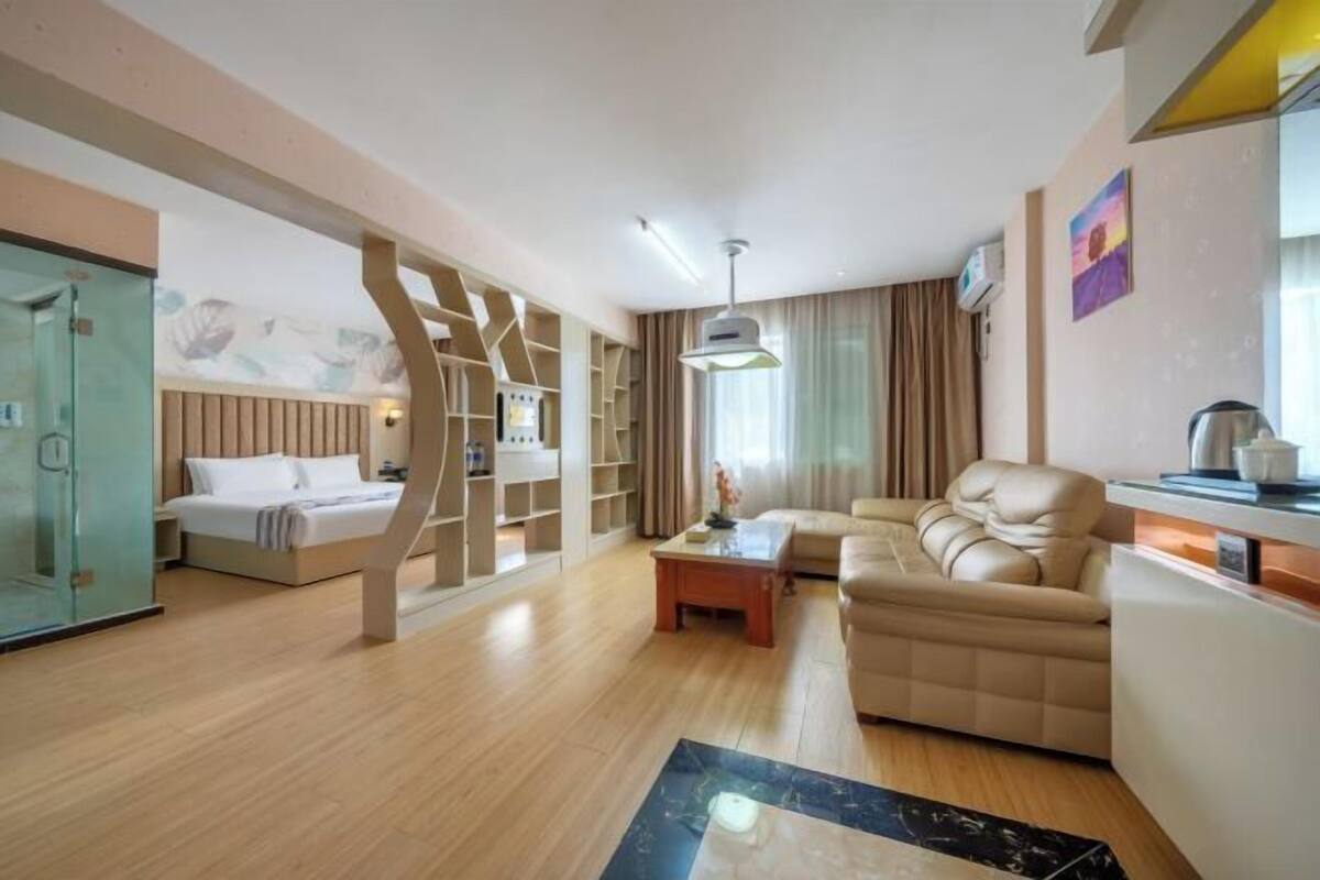 Een moderne hotelkamer met een bed, een bank, een salontafel en een douchecabine van glas.