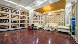A spacious living area with a polished wooden floor, elegant white sofas, and a decorative wall with geometric patterns.