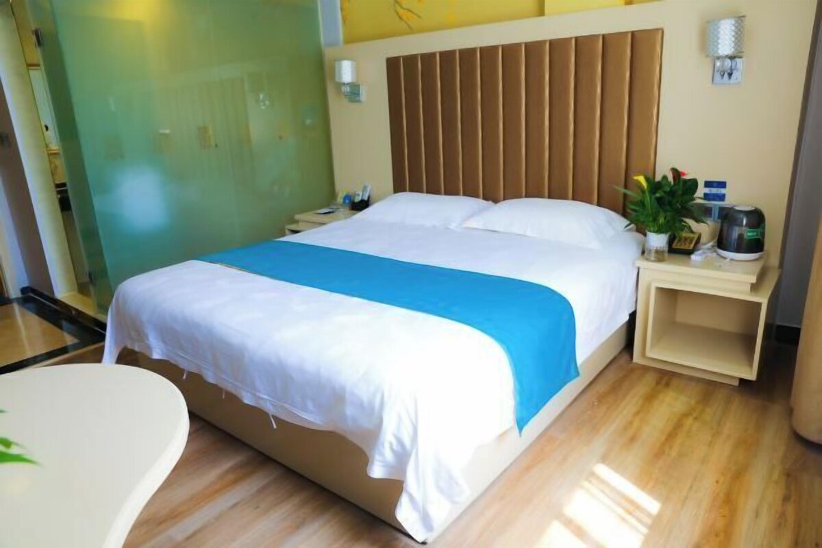 A hotel room with a bed, bedside table, and a small desk with a chair.