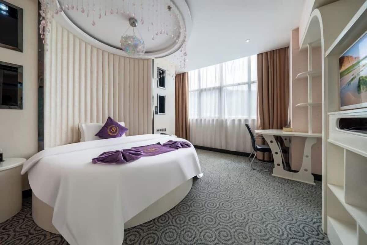 Een hotelkamer met een bed, een bureau en een televisietoestel op een standaard.