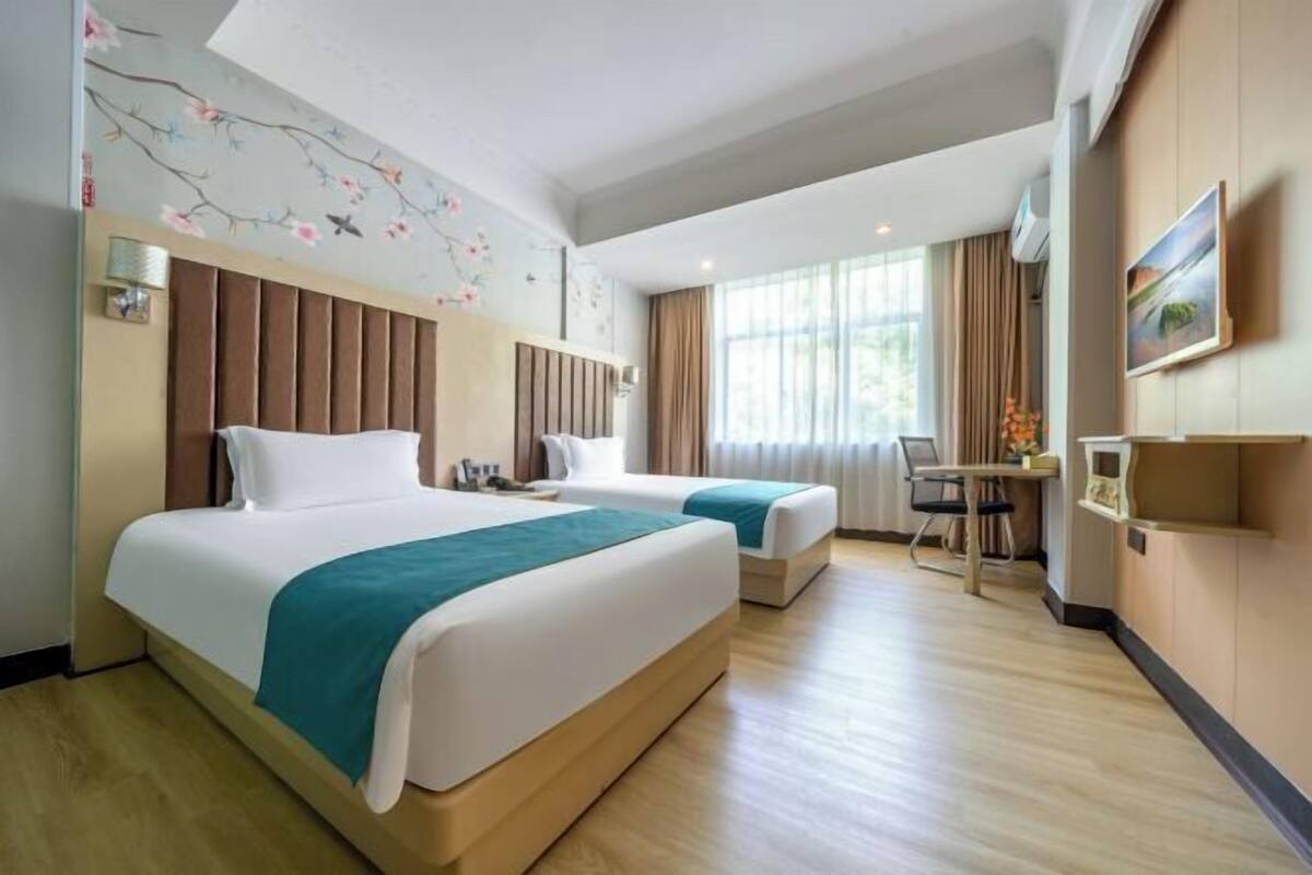 Een hotelkamer met twee bedden, een bureau en een stoel.