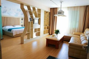 A modern hotel room with a bed, a sofa, a coffee table, and built-in shelves. - Jing Chen Holiday Hotel (Xilin Yingbin Road) (Xilin)