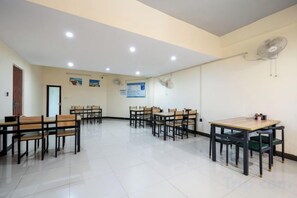 A conference room with multiple tables and chairs, a door, and a wall-mounted fan. - Jing Chen Holiday Hotel (Xilin Yingbin Road) (Xilin)