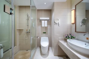 Un baño moderno con cabina de ducha de vidrio, inodoro blanco, lavamanos grande y un espejo.
