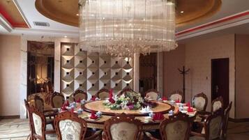 Un comedor formal con una mesa redonda, sillas ornamentadas y una gran lámpara de araña.