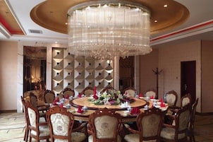 Un comedor formal con una mesa redonda, sillas ornamentadas y una gran lámpara de araña.