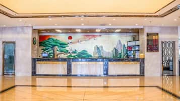 Zona de recepción con un mural grande, una mesa de recepción y piso de baldosas.