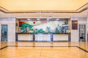 Zona de recepción con un mural grande, una mesa de recepción y piso de baldosas.