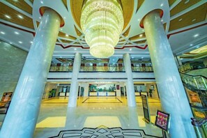A spacious lobby with a large chandelier, multiple floors, and a central atrium. - He Huang Pearl Hotel (Linxia)