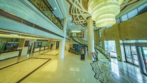 A spacious atrium with a central staircase, high ceilings, and decorative ceiling patterns.