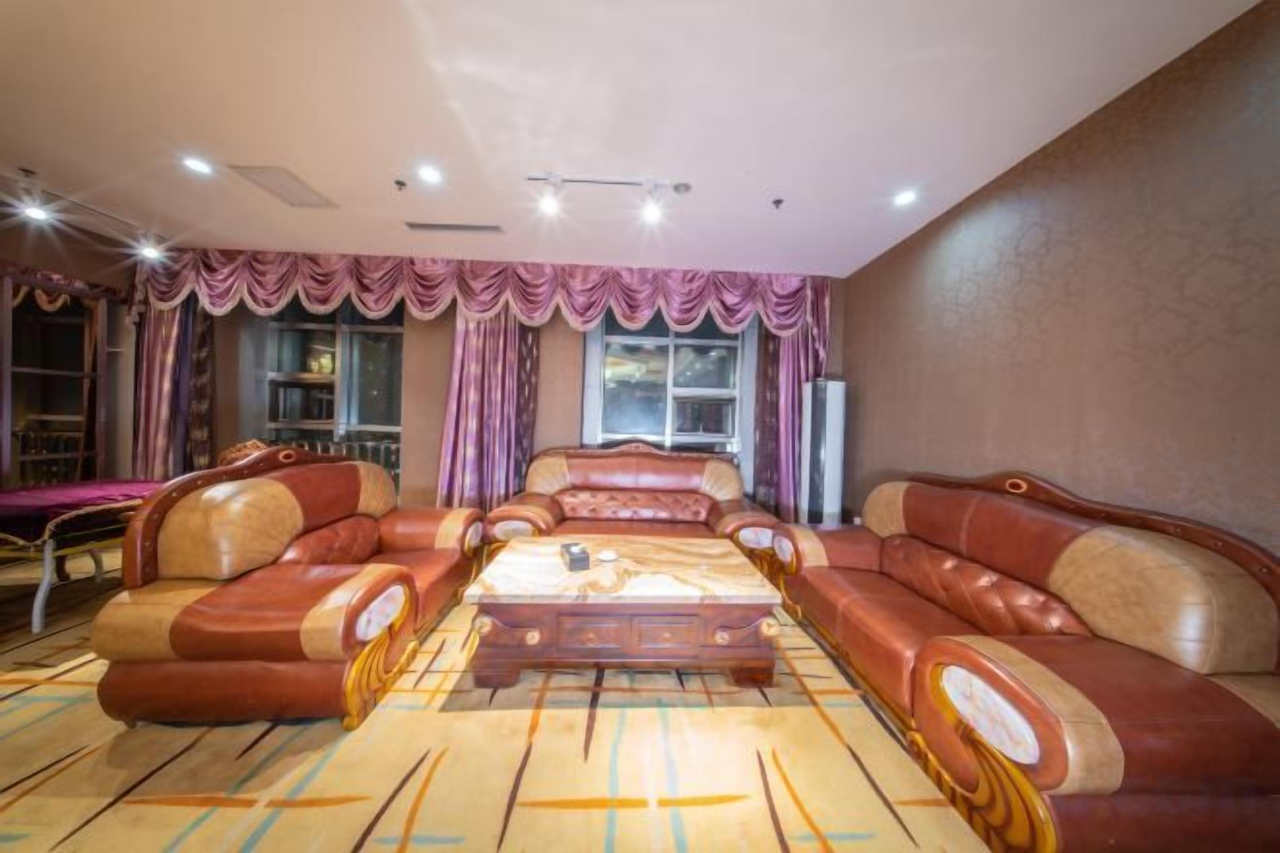 A hotel room with a large sofa set, a dining table, and a carpeted floor.