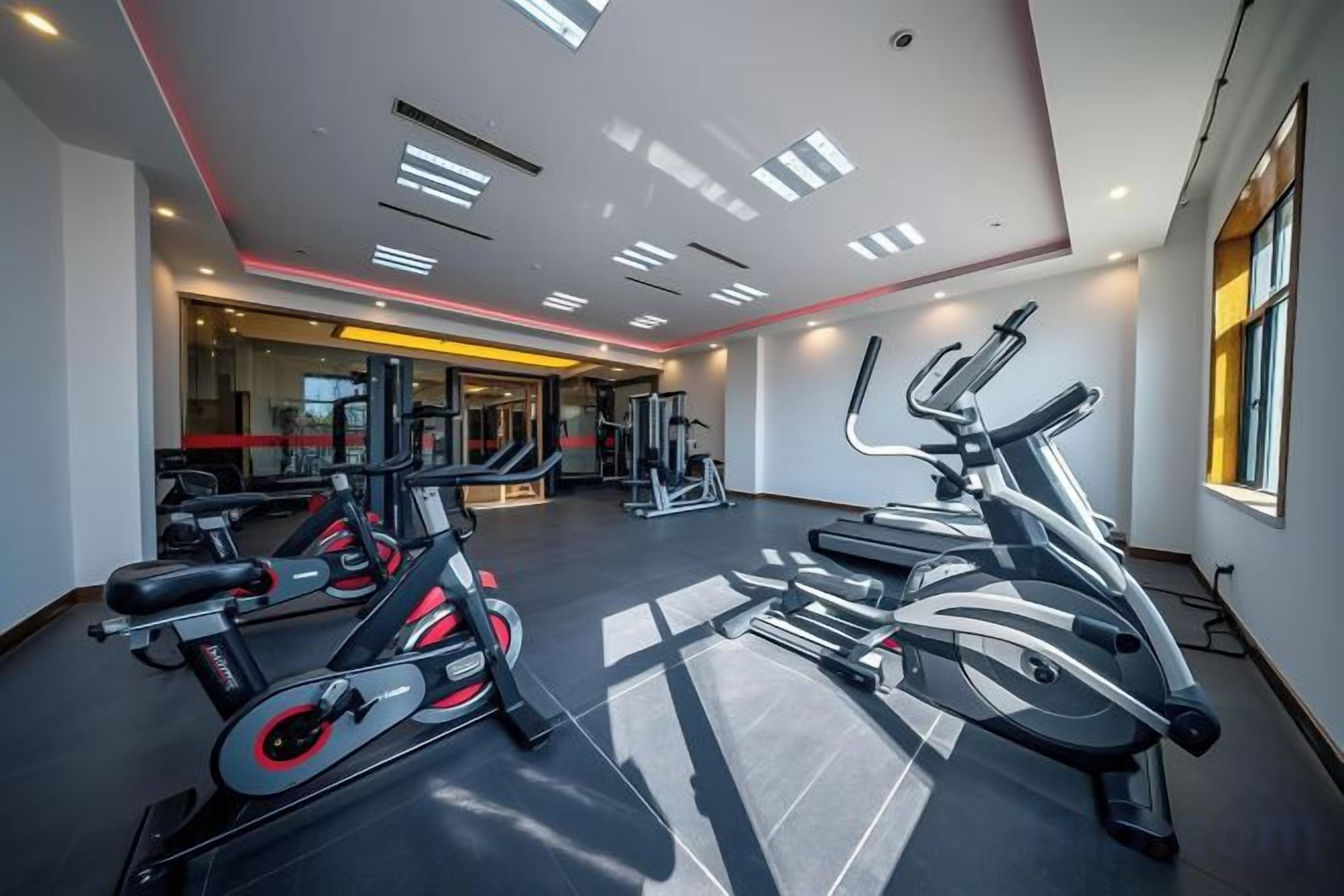 Un gimnasio con equipamiento de ejercicio, un espejo grande y una ventana.