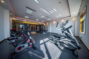 Un gimnasio con equipamiento de ejercicio, un espejo grande y una ventana.
