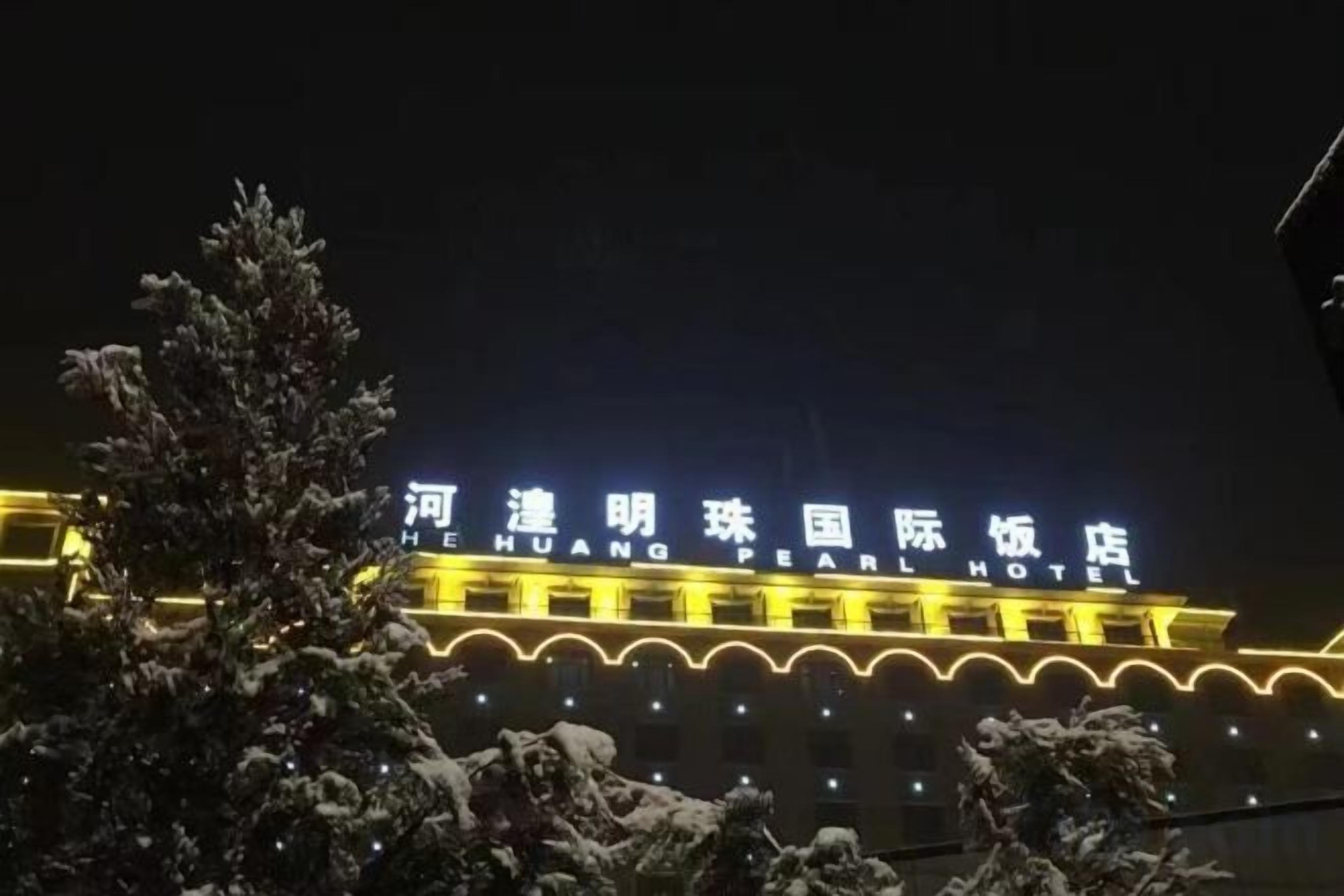 Un hotel con señalización iluminada y un paisaje cubierto de nieve.