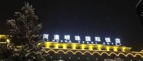 Un hotel con señalización iluminada y un paisaje cubierto de nieve.