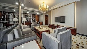 A modern living room with a chandelier, sofas, a coffee table, a flat-screen TV, and a bookshelf.