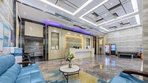 A modern hotel lobby with a reception desk, seating area, and a decorative vase on a round table. - Super Comfy (Shenzhen)