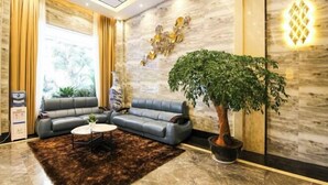 A modern lobby with a sectional sofa, a coffee table, a large potted plant, and a decorative wall piece. - Super Comfy (Shenzhen)