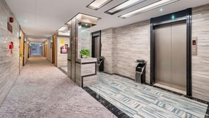 A modern hotel lobby with a marble floor, a reception desk, and an elevator. - Super Comfy (Shenzhen)