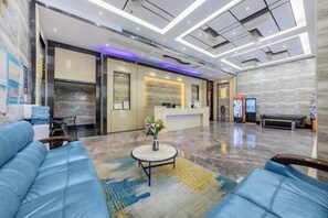 A hotel lobby with a reception desk, seating area, and a large mirror. - Super Comfy (Shenzhen)