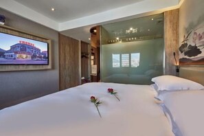 A hotel room with a bed, a television mounted on the wall, and a painting on the wall. - Xueyuan Hotel (Wenzhou)