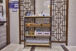 A reception area with a reception desk, a decorative screen, and a shelf with baskets and bottles. - Xueyuan Hotel (Wenzhou)