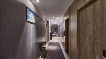 Un pasillo con piso alfombrado, puertas de madera y un cuadro en la pared.