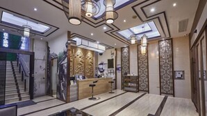 Een moderne hotel lobby met een receptiebalie, bar en zitgedeelte.