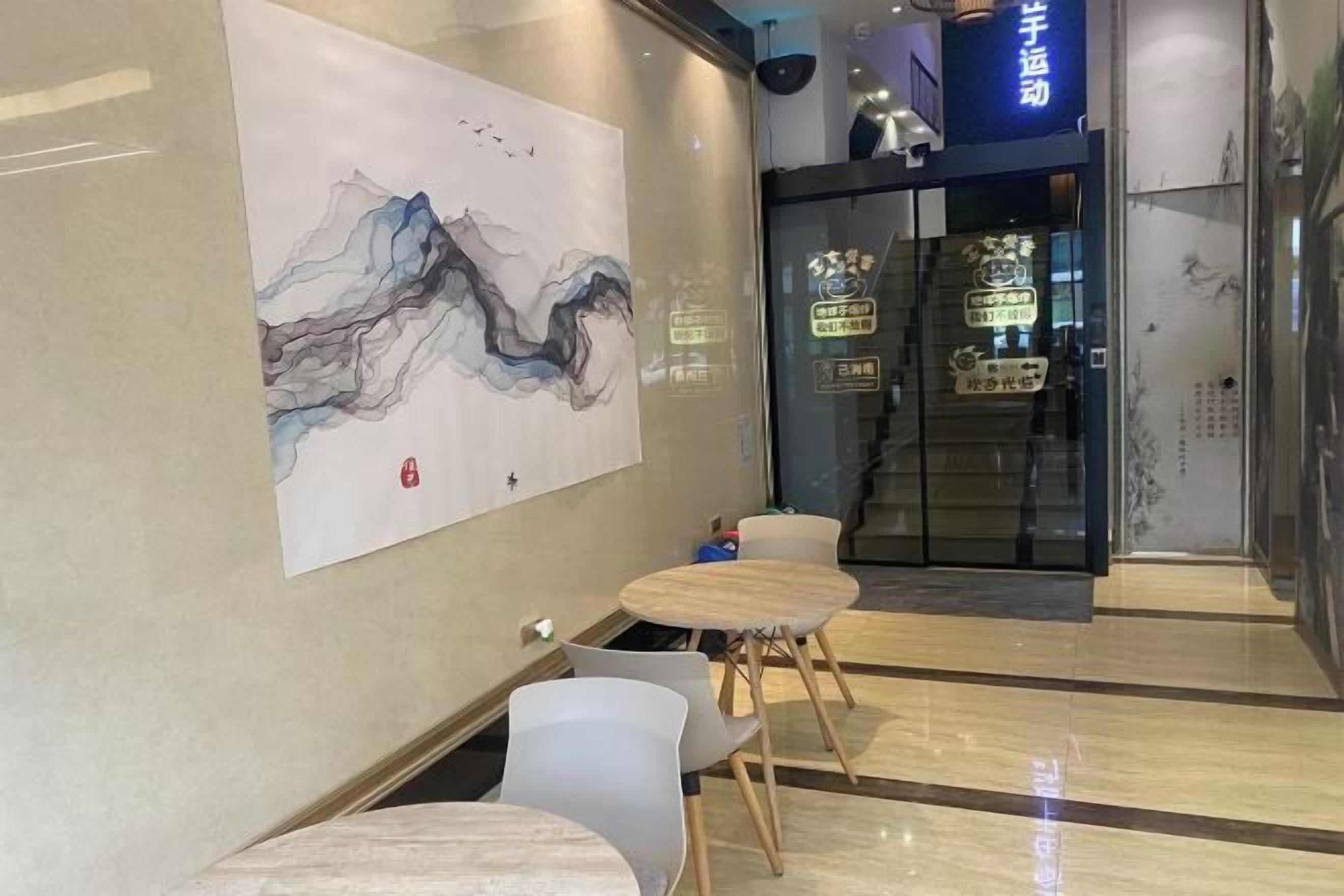 A modern interior with a large abstract painting, a reception desk, and a sign for a fitness center.