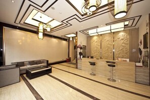 Een moderne lobby met een receptiebalie, zithoek en decoratieve verlichting.