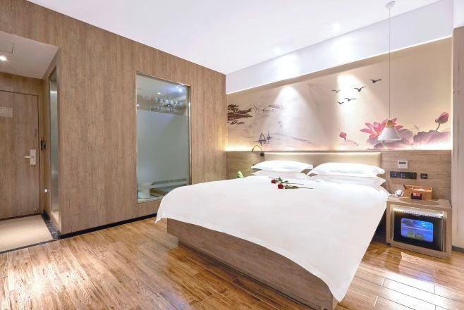 Un dormitorio moderno con una cama grande, una mesita de noche con televisor y un calentador fijado a la pared.
