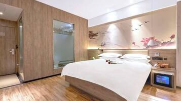 Un dormitorio moderno con una cama grande, una mesita de noche con televisor y un calentador fijado a la pared.