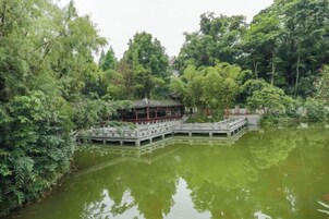 Un pabellón tradicional junto a un lago, rodeado de vegetación exuberante.