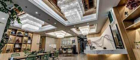 A modern hotel lobby with a reception desk, seating area, and decorative lighting.