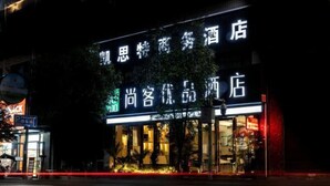 A hotel with illuminated signage in a foreign language, a visible entrance, and a parking area in the foreground. - Kester Business Hotel (Qianxi)