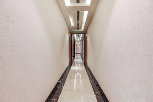 A corridor with a reflective floor, leading to a door at the end.