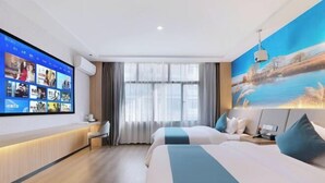 A hotel room with a large digital screen displaying content, a bed with a view of a painting, and a desk with a chair. - Kester Business Hotel (Qianxi)