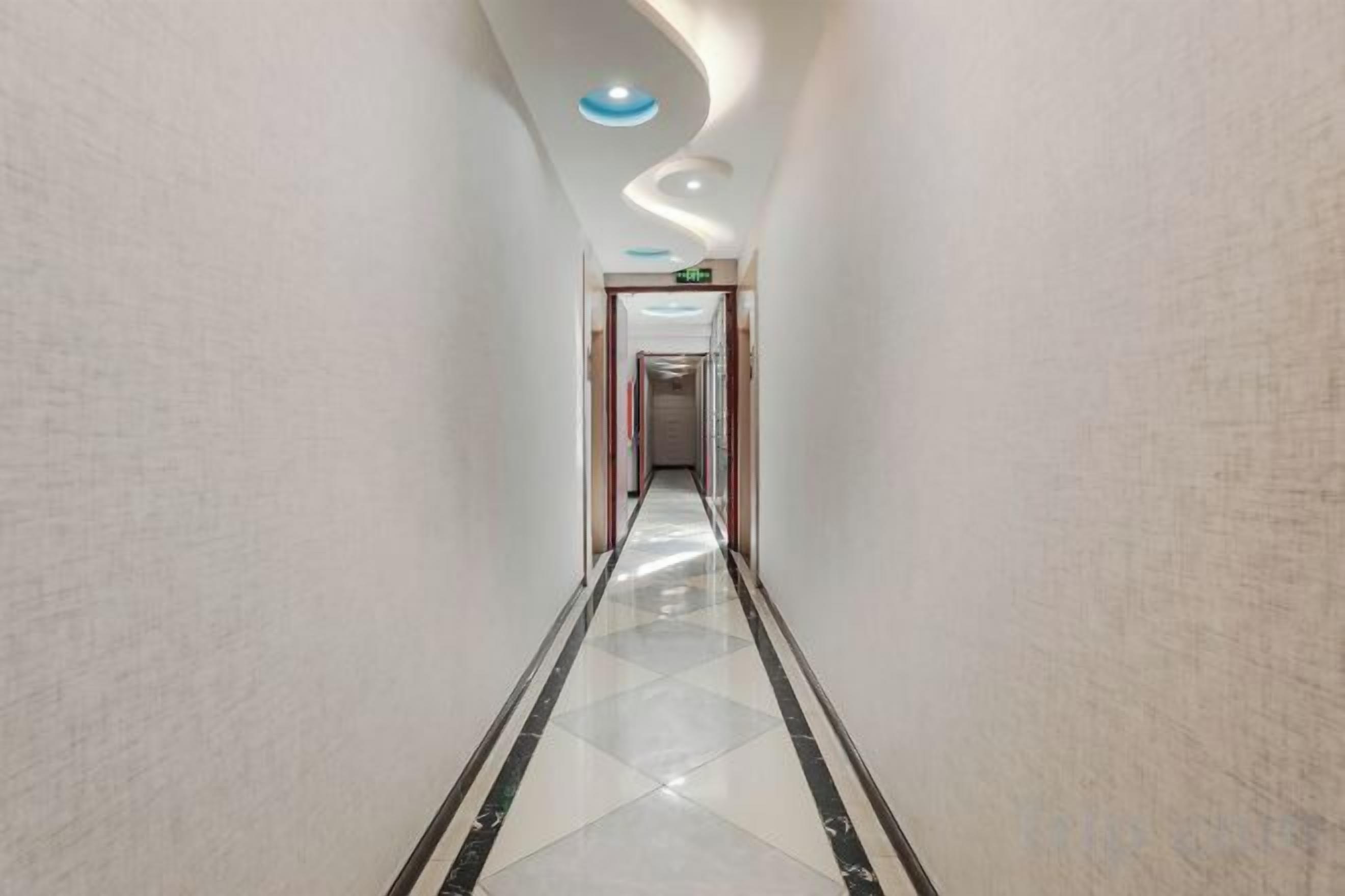 A corridor with a polished floor, a curved ceiling, and a door at the end.