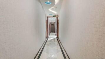 A corridor with a polished floor, a curved ceiling, and a door at the end.