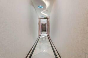 A corridor with a polished floor, a curved ceiling, and a door at the end. - Kester Business Hotel (Qianxi)