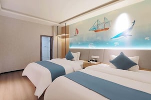 A hotel room with two beds, a mural of sailboats and sea creatures, and a wooden floor.