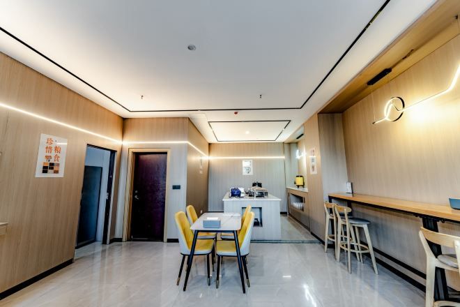 A modern hotel room with a dining area, a kitchen, and a bar.