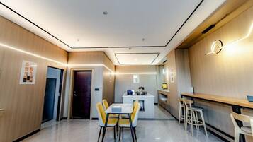 A modern hotel room with a dining area, a kitchen, and a bar.