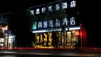 A hotel with illuminated signage, a visible entrance, and a street view.
