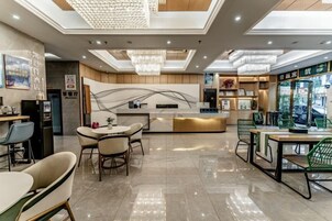 Un moderno vestíbulo de hotel con mostrador de recepción, zona de estar y vista a la calle.