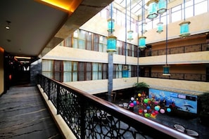 A multi-level atrium with a central pool area, featuring a railing and hanging lamps. - Xiya Inn (Lanzhou)