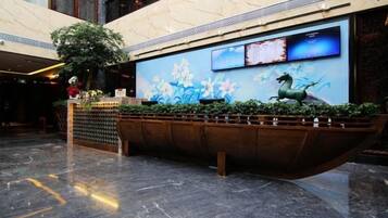 Un vestíbulo con una gran pantalla digital, un mostrador de recepción y una planta.